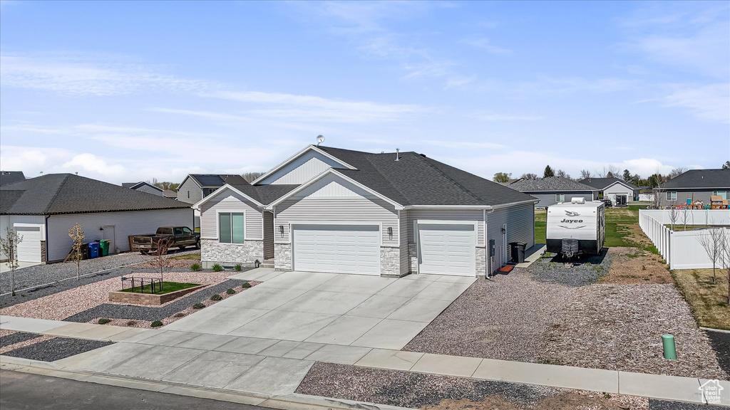 View of front of home featuring a garage, concrete driveway, stone siding, a residential view, and a shingled roof