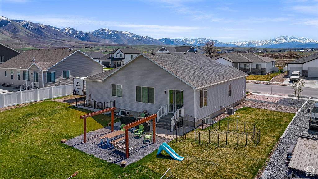 Back of house featuring a playground, a mountain view, a residential view, and a shingled roof