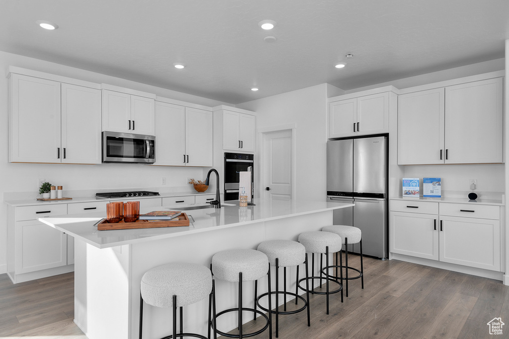 Kitchen featuring a breakfast bar, a sink, light wood-style floors, and appliances with stainless steel finishes
