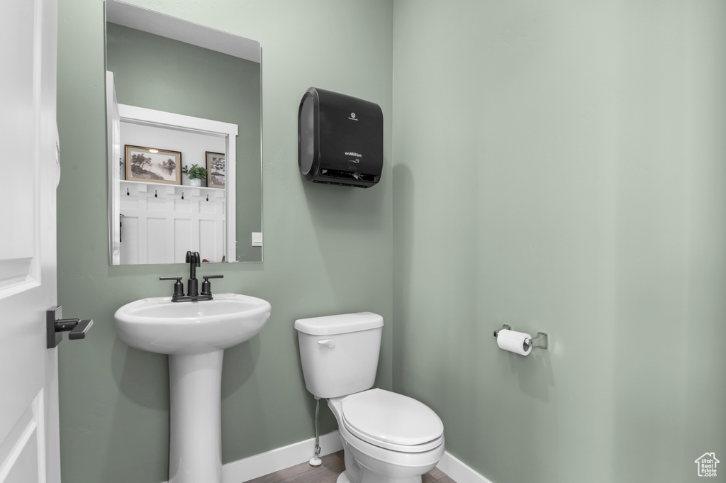 Half bath featuring baseboards, toilet, and a sink