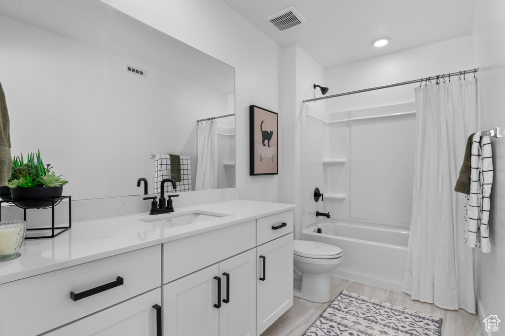 Full bath with shower / tub combo with curtain, visible vents, toilet, and vanity