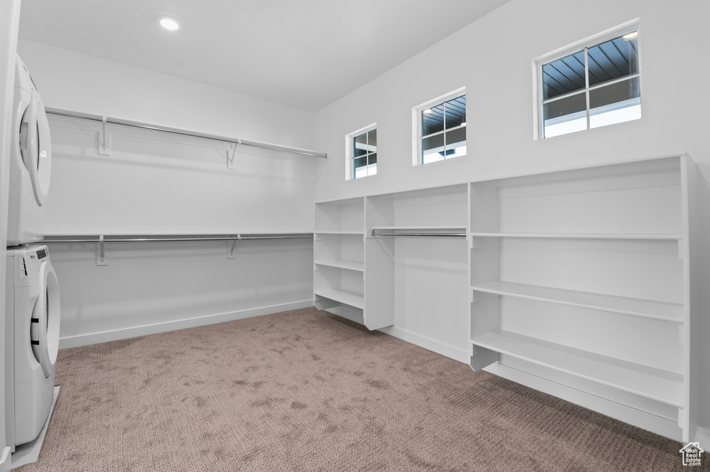 Spacious closet with stacked washer and clothes dryer and carpet floors