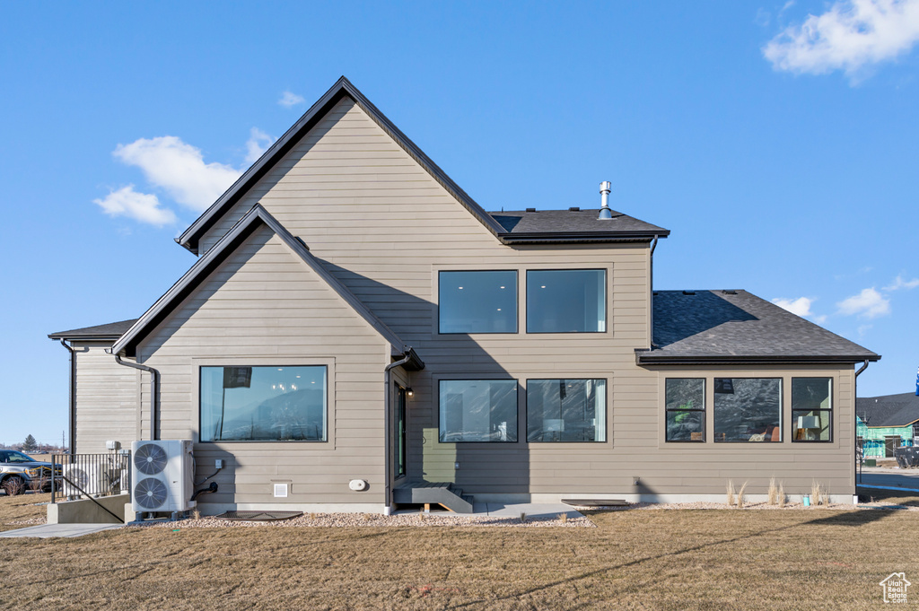 Back of house with a lawn, ac unit, and roof with shingles