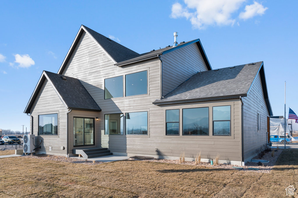 Rear view of house with a lawn, a shingled roof, and entry steps