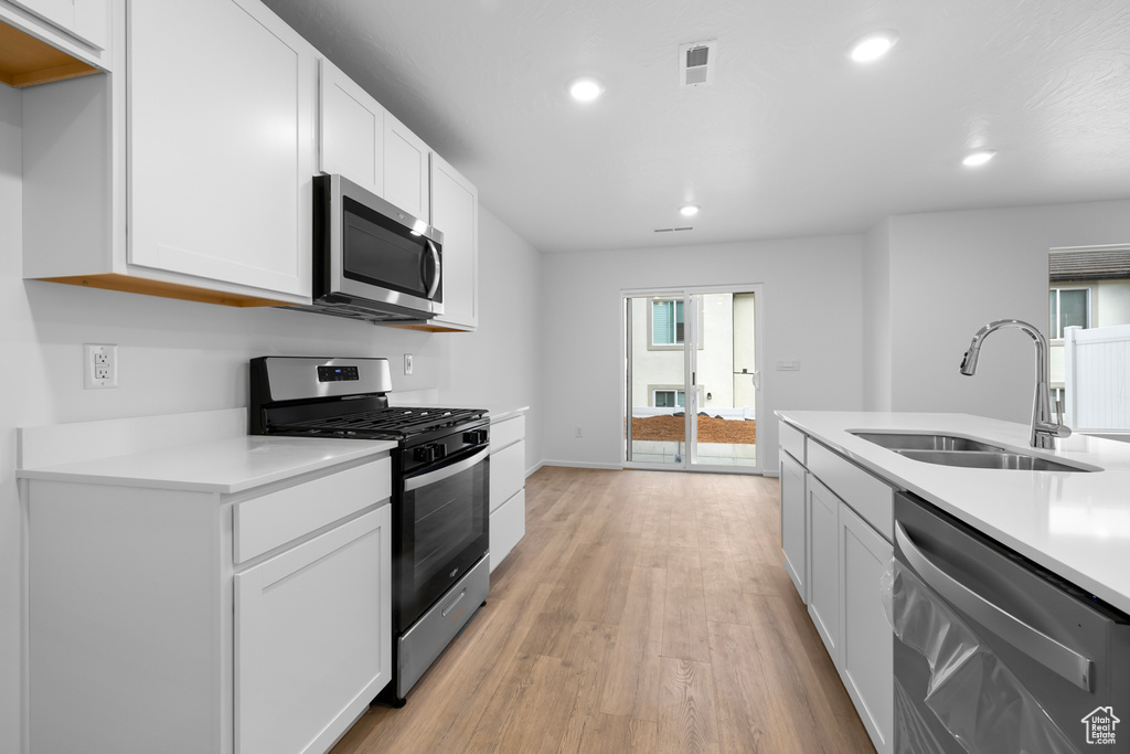 Kitchen with light countertops, a sink, appliances with stainless steel finishes, and visible vents