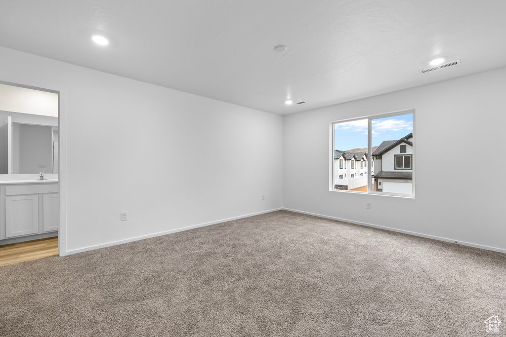 Spare room with light carpet, baseboards, visible vents, and recessed lighting