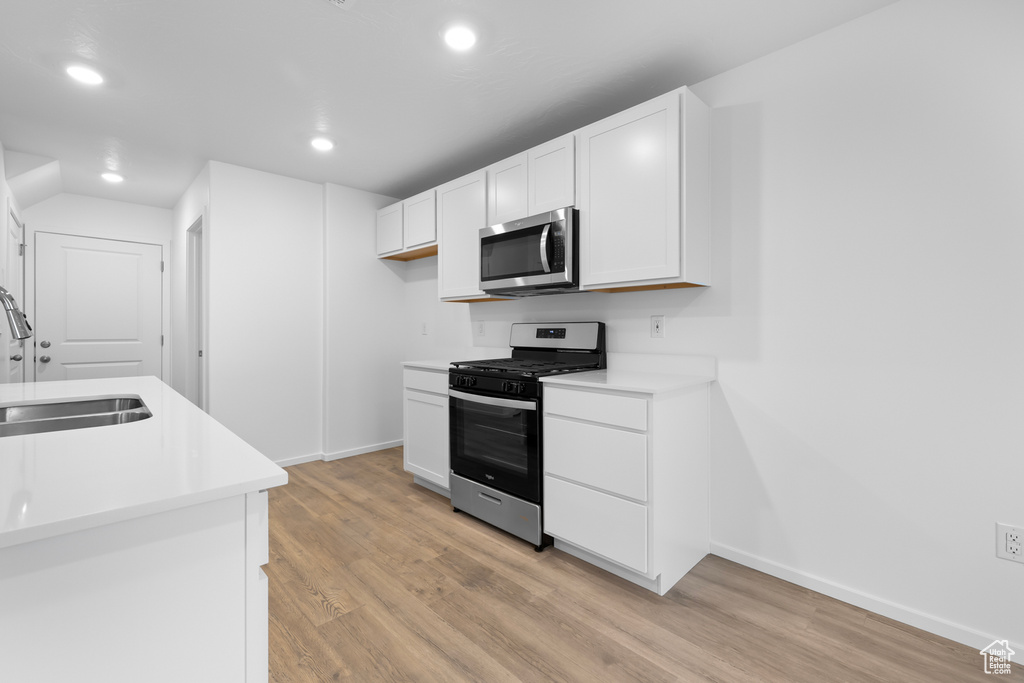 Kitchen featuring recessed lighting, stainless steel appliances, a sink, light wood finished floors, and white cabinets
