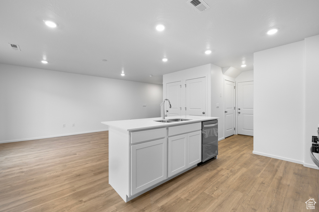 Kitchen featuring an island with sink, visible vents, light wood-style flooring, and a sink