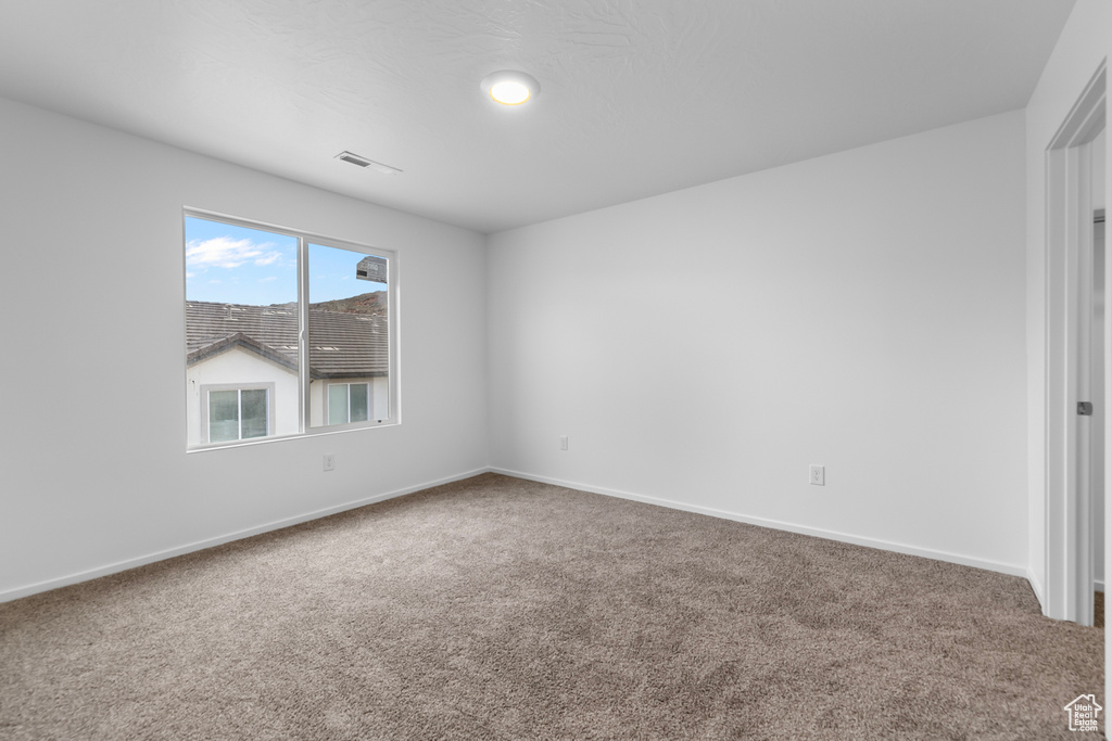 Spare room with baseboards, visible vents, and carpet