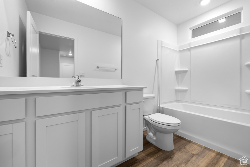 Bathroom featuring  shower combination, toilet, vanity, and wood finished floors