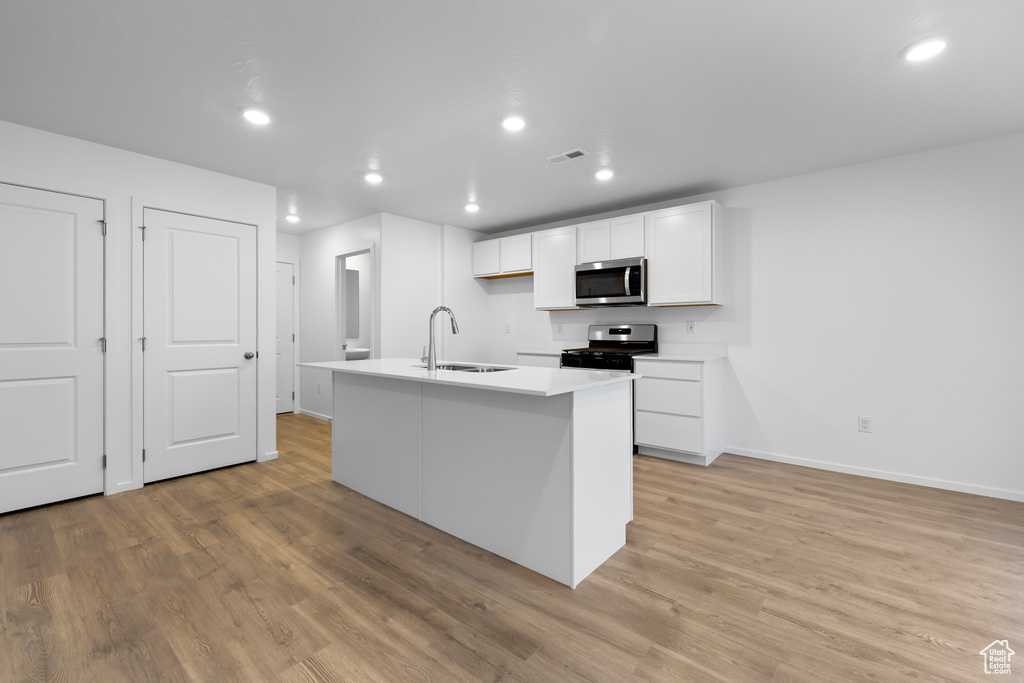 Kitchen featuring a sink, appliances with stainless steel finishes, white cabinets, light wood-style floors, and recessed lighting