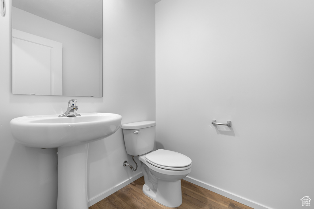 Bathroom with baseboards, wood finished floors, and toilet