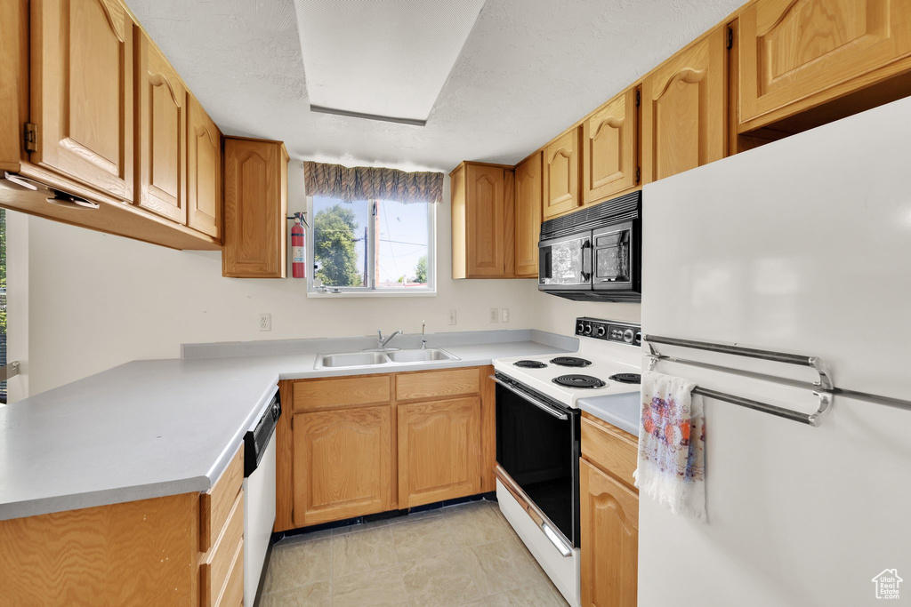 Kitchen featuring white appliances, a sink, and light countertops