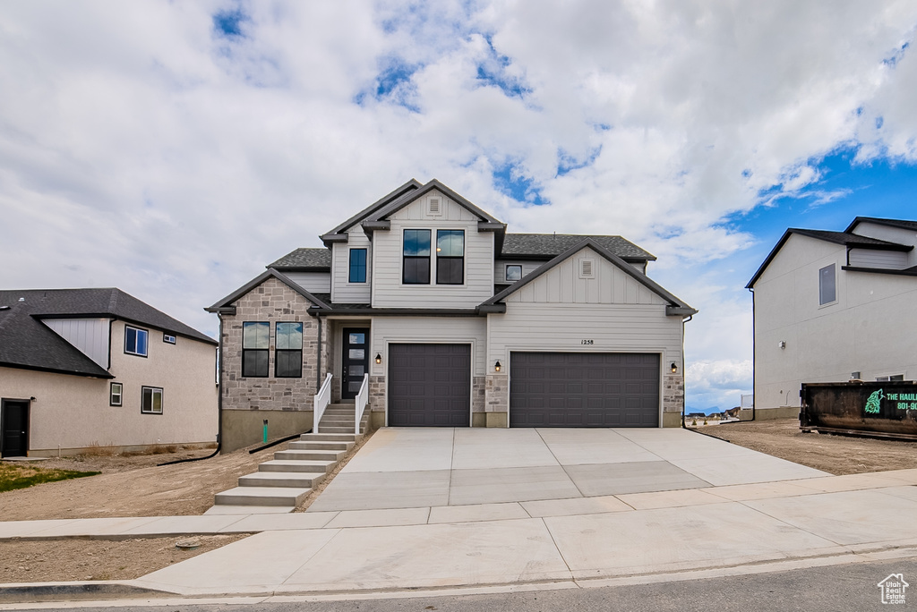 View of front facade with a garage, board and batten siding, and concrete driveway