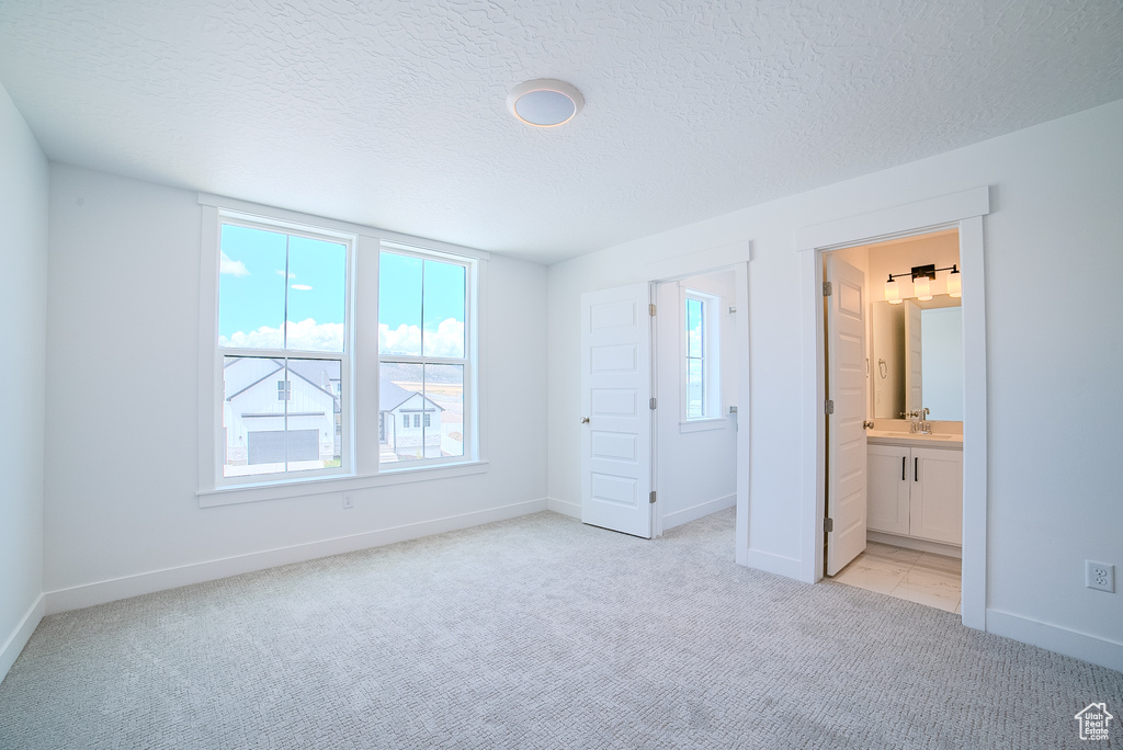 Unfurnished bedroom with light colored carpet, a textured ceiling, and baseboards