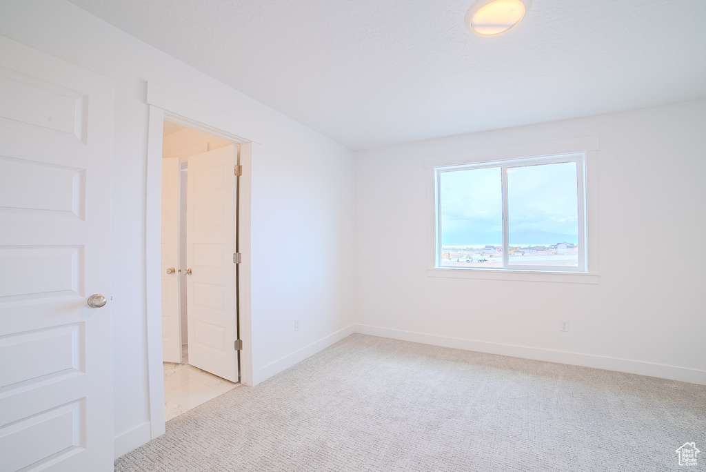 Unfurnished room featuring baseboards and light carpet