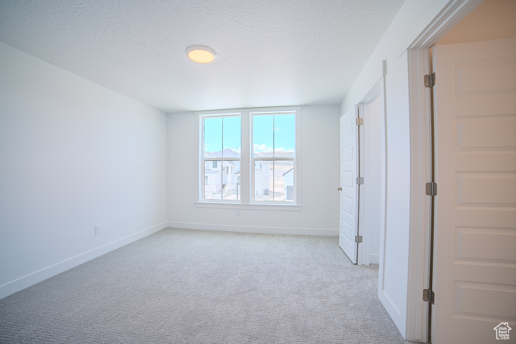 Unfurnished bedroom featuring a textured ceiling, baseboards, and light carpet