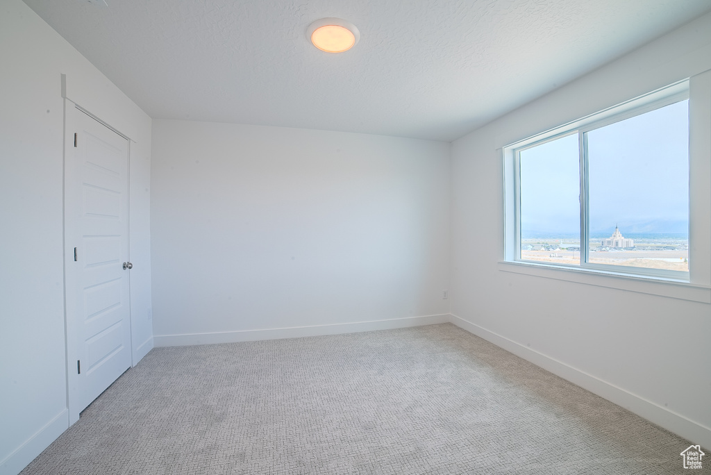 Unfurnished room with baseboards and light carpet