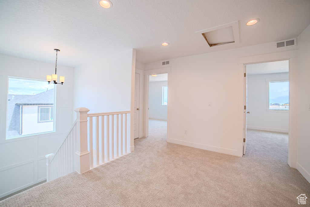 Spare room featuring visible vents, recessed lighting, light carpet, and an inviting chandelier