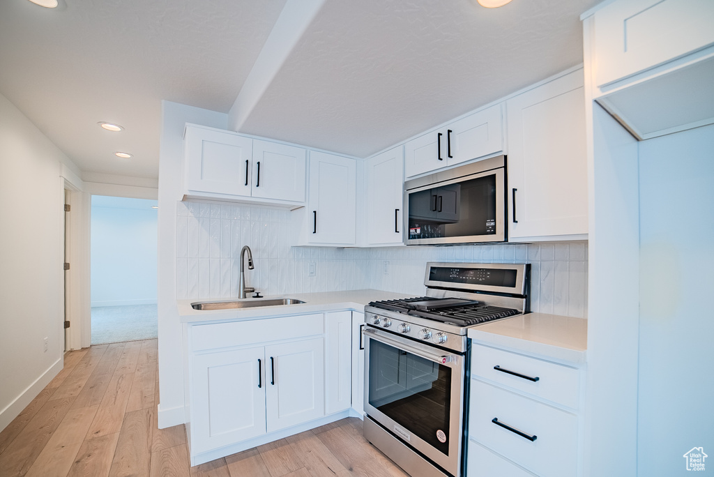 Kitchen with a sink, light countertops, stainless steel appliances, recessed lighting, and tasteful backsplash