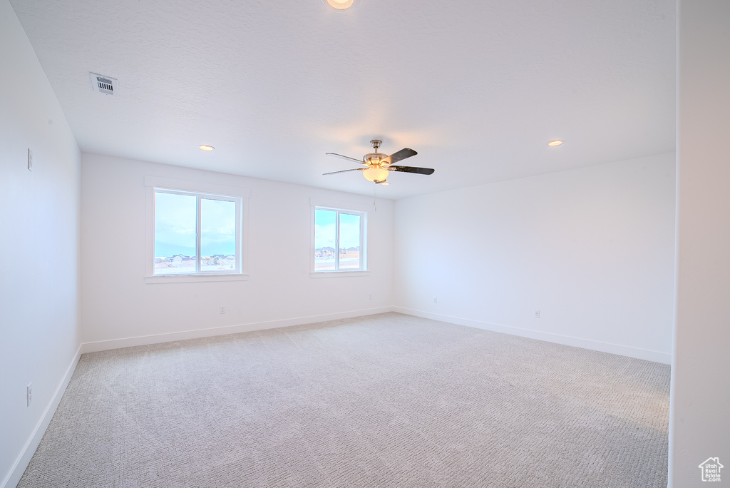 Spare room with baseboards, light colored carpet, recessed lighting, and visible vents