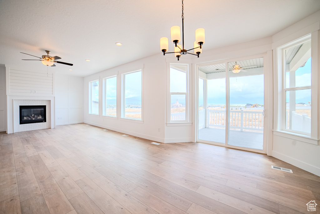 Unfurnished living room featuring baseboards, ceiling fan with notable chandelier, a large fireplace, and visible vents