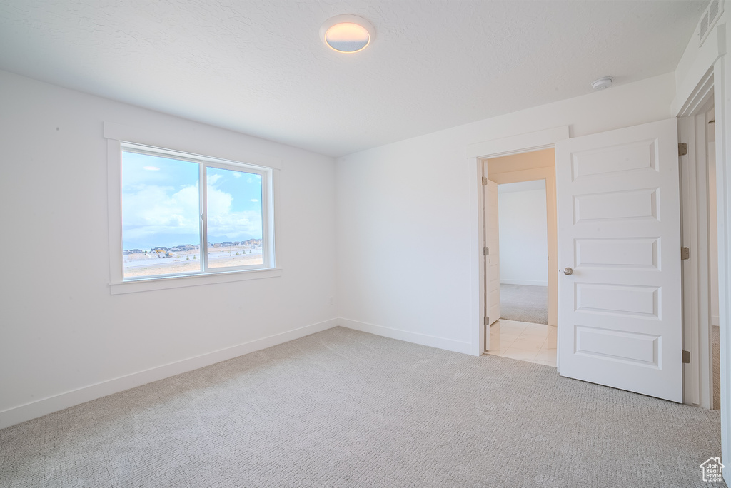 Unfurnished bedroom with baseboards and light carpet