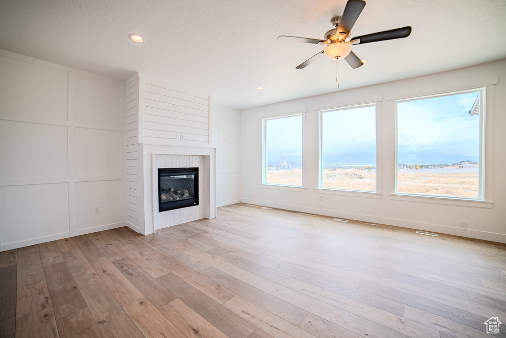 Unfurnished living room with a ceiling fan, a glass covered fireplace, recessed lighting, and light wood-type flooring