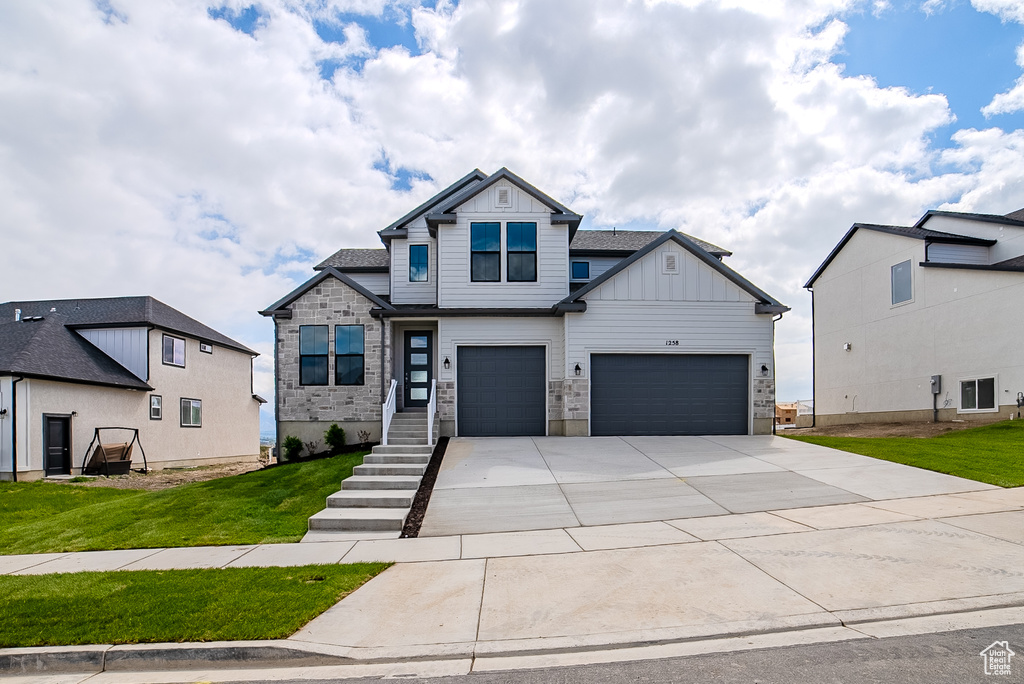 Craftsman house featuring concrete driveway, board and batten siding, a garage, and a front lawn