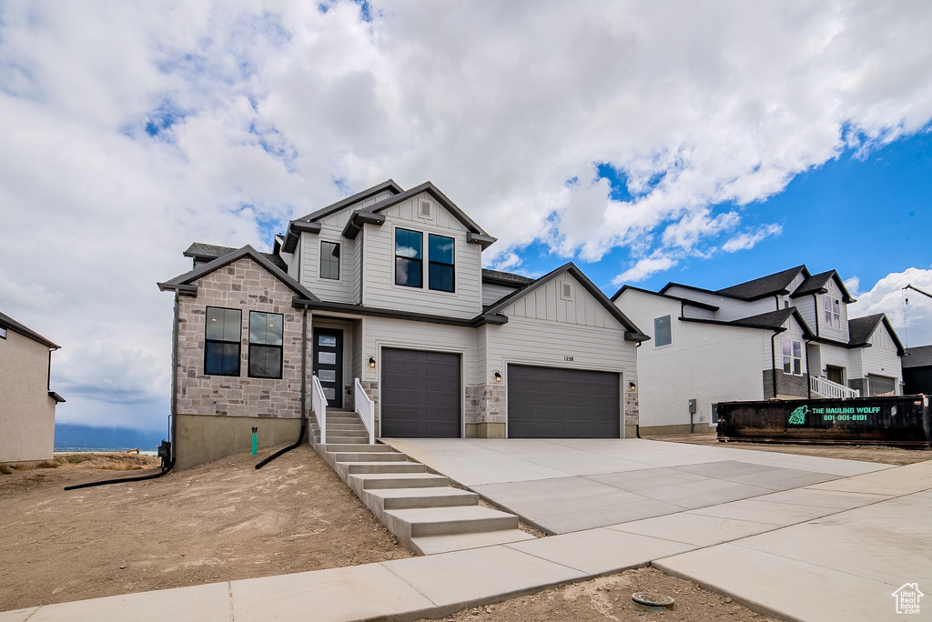 View of front of property featuring a garage, board and batten siding, stone siding, and concrete driveway