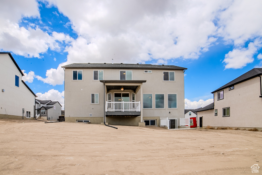 Rear view of house featuring stucco siding and a balcony