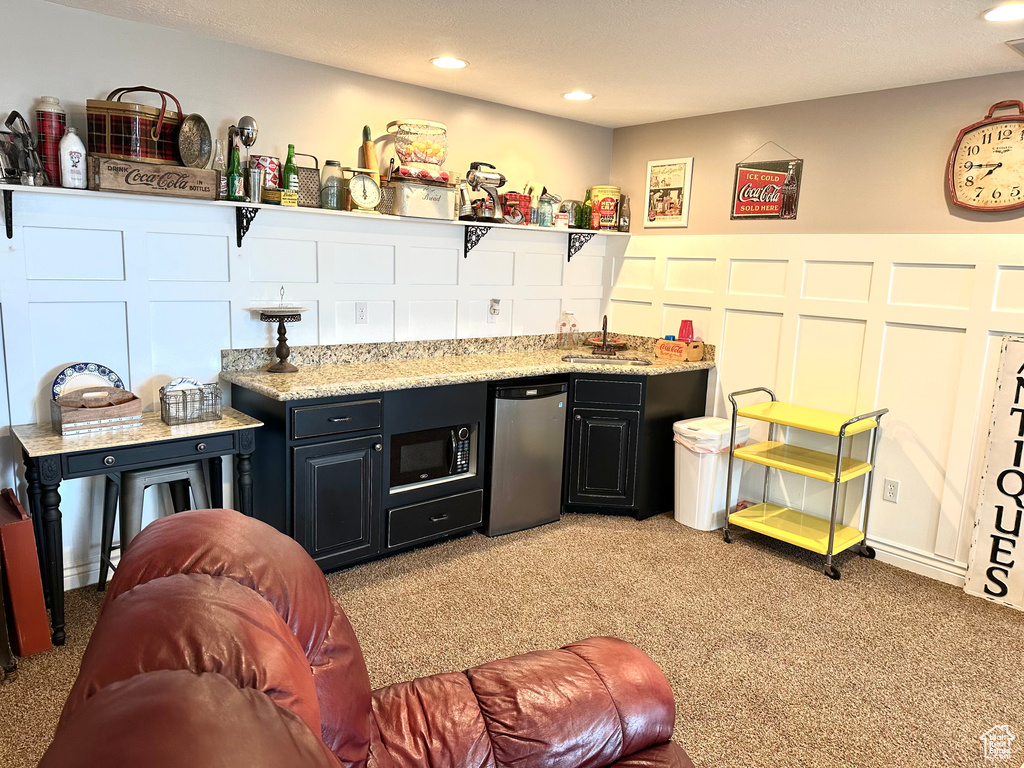 Indoor wet bar featuring light carpet, black microwave, fridge, and recessed lighting