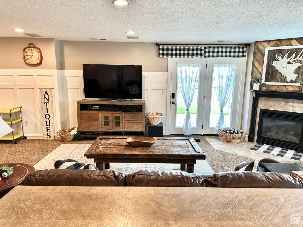 Carpeted living room with a textured ceiling, a tile fireplace, and a decorative wall