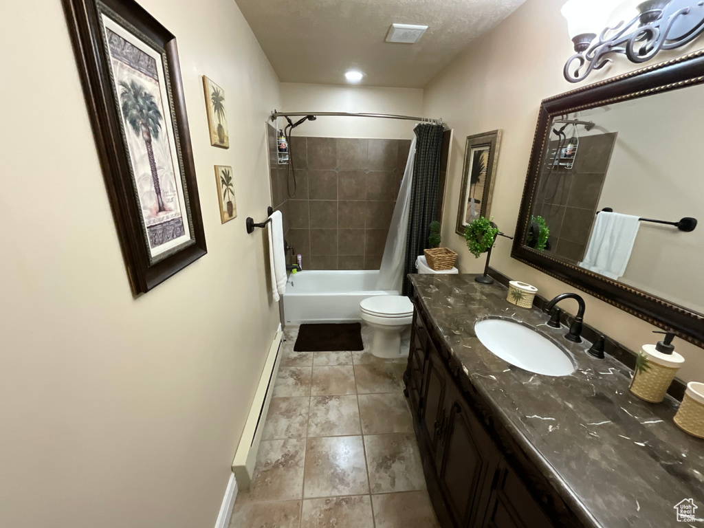Bathroom featuring toilet, vanity, shower / bath combo, baseboards, and a baseboard heating unit
