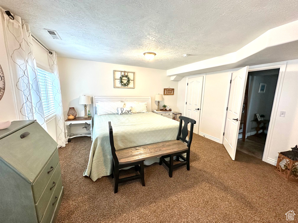 Bedroom featuring a textured ceiling and dark colored carpet