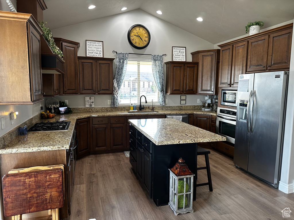 Kitchen with stainless steel appliances, light wood-style floors, a center island, and a sink