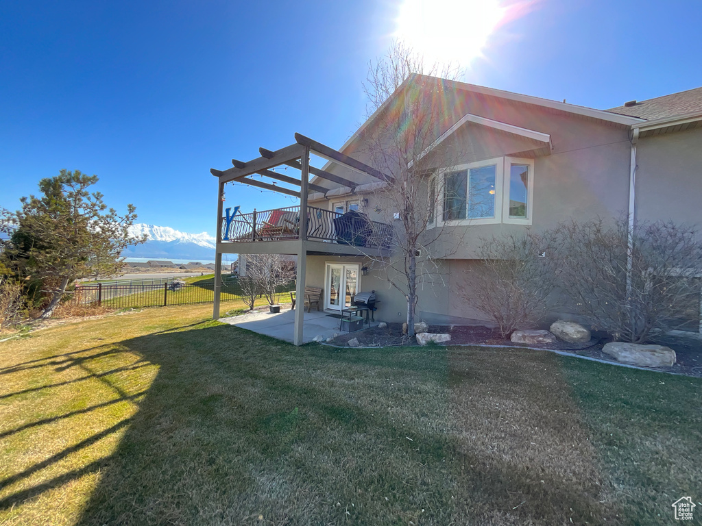 Rear view of property with stucco siding, fence, a patio, french doors, and a yard