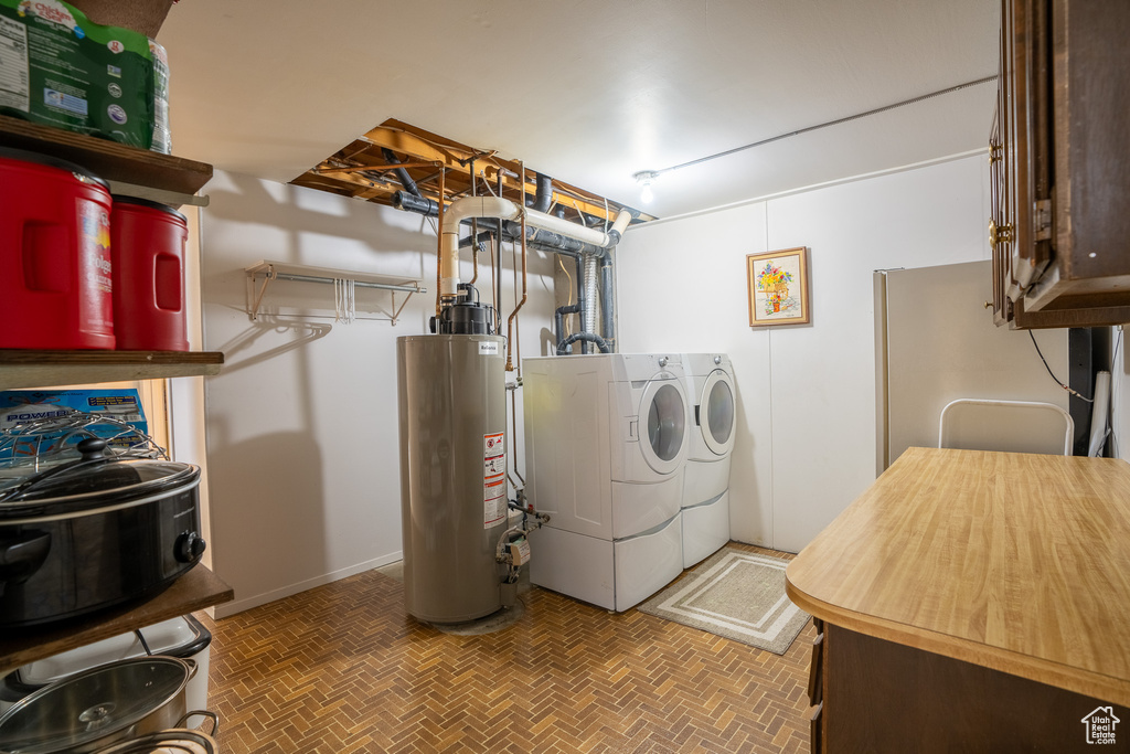 Laundry room with washing machine and clothes dryer, gas water heater, and cabinet space