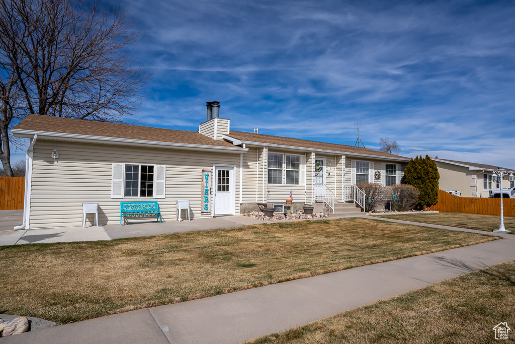 Exterior space featuring a chimney, a shingled roof, fence, and a yard