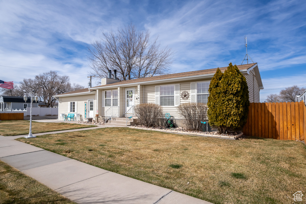 View of front of property with entry steps, fence, and a front yard