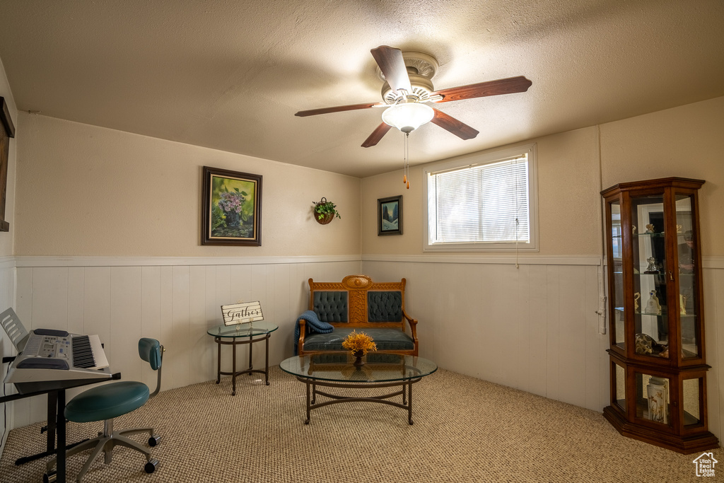 Sitting room with a textured ceiling, wainscoting, carpet floors, and a ceiling fan
