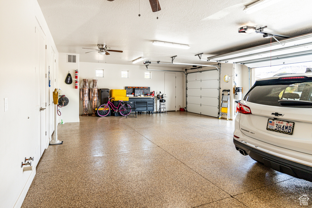 Garage featuring a garage door opener, visible vents, and a ceiling fan