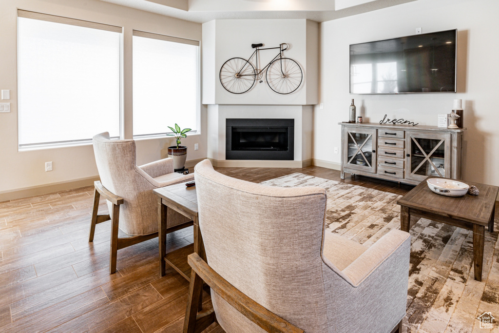 Living room featuring baseboards, a glass covered fireplace, and wood finished floors