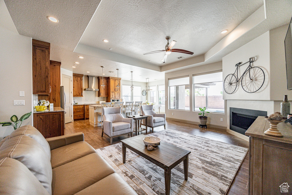 Living area with baseboards, a fireplace, recessed lighting, a ceiling fan, and light wood-type flooring
