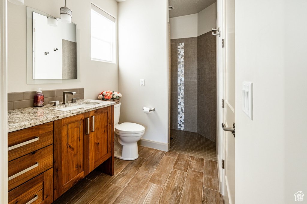 Bathroom featuring vanity, toilet, baseboards, walk in shower, and wood tiled floor
