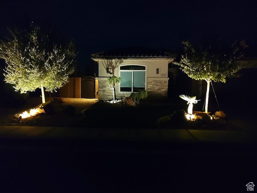 View of front of property with stucco siding, stone siding, a gate, and a tile roof