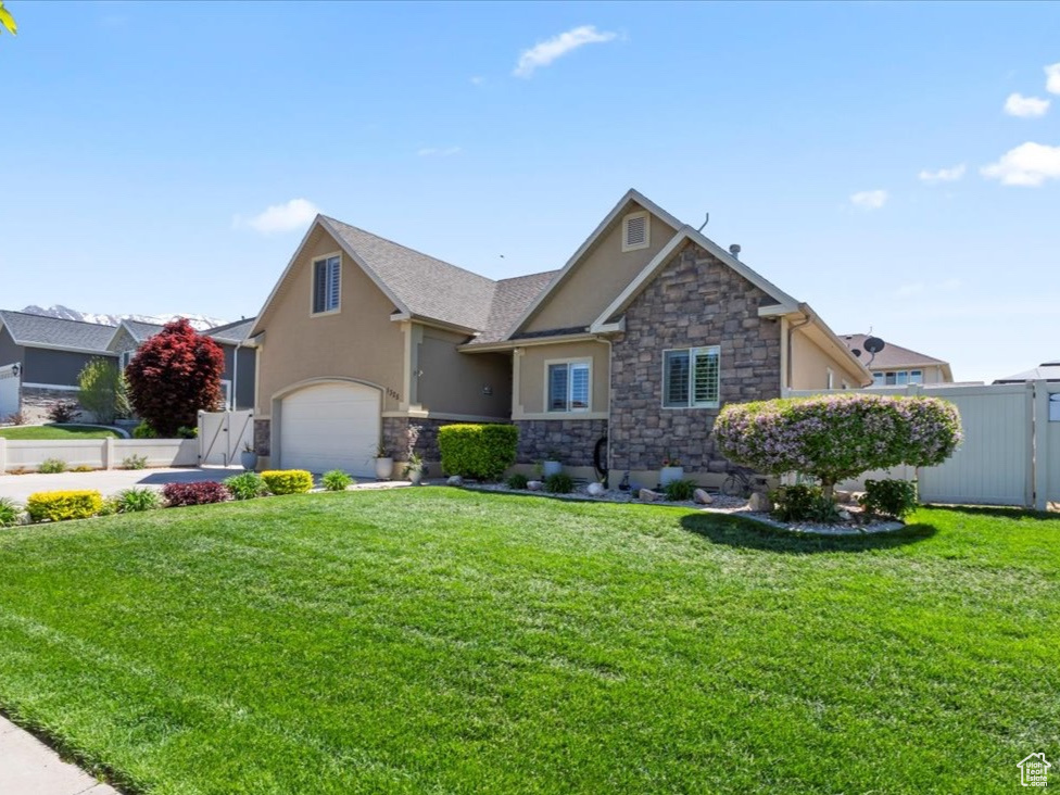 View of front of property featuring stucco siding, stone siding, an attached garage, and concrete driveway