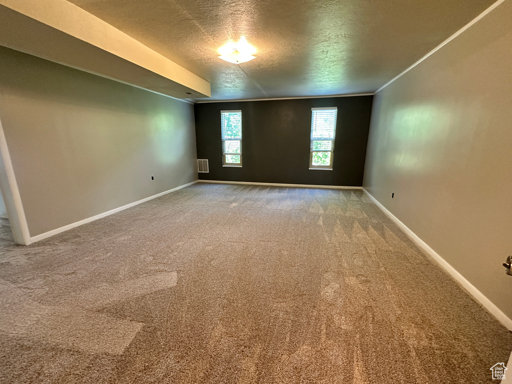 Unfurnished room with a textured ceiling, baseboards, and carpet