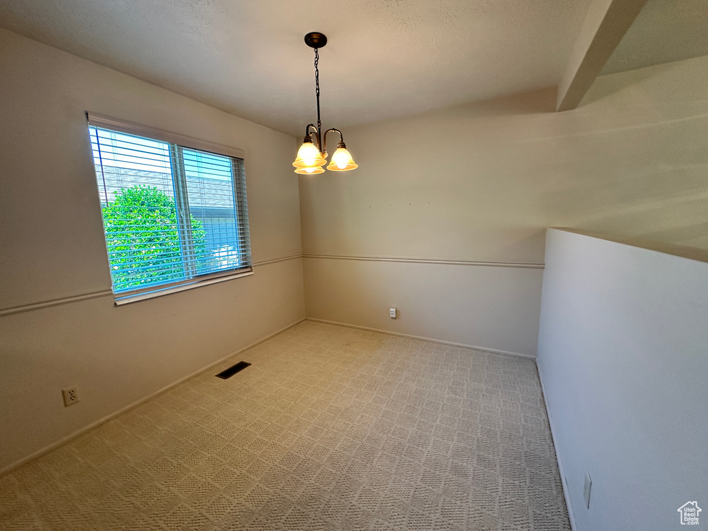 Carpeted empty room with a chandelier