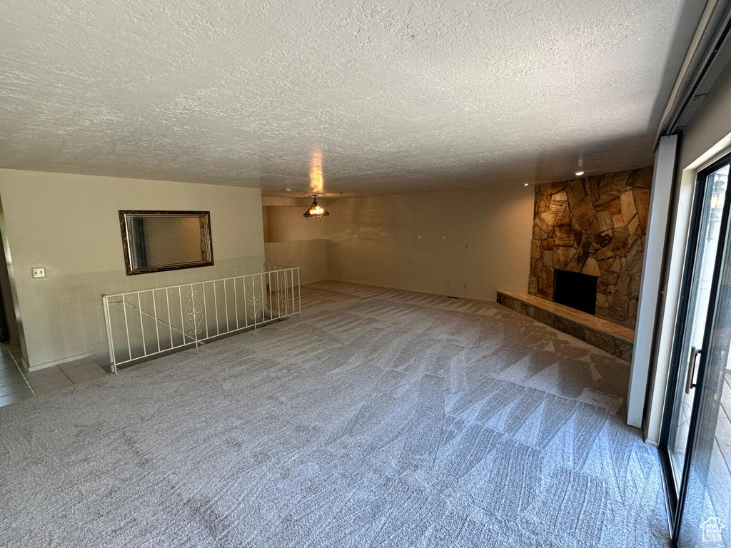 Unfurnished living room featuring carpet floors, a textured ceiling, and a fireplace